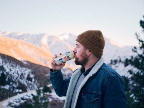 man drinking Coors in the mountains